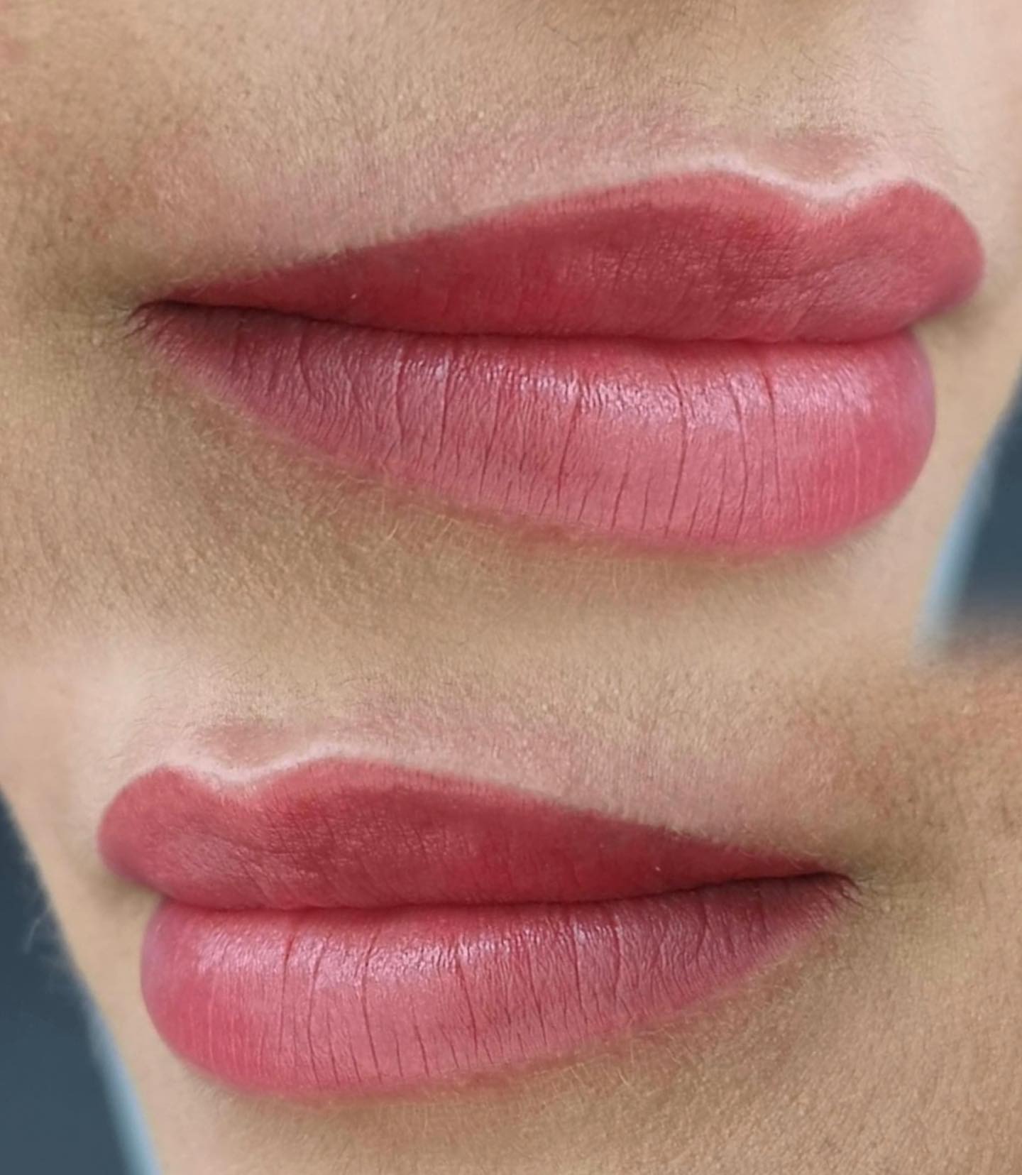 Zbliżenie na usta po zabiegu makijażu permanentnego z widoczną linią konturu i wypełnieniem kolorem w odcieniach różu.