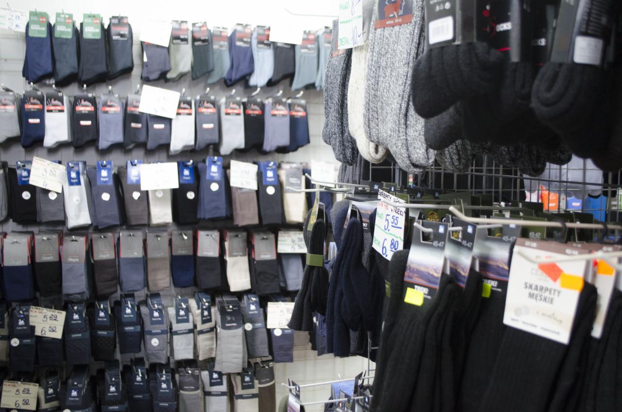 Ekspozycja skarpet w sklepie, różne kolory i wzory, niektóre z cenami na etykietach, widoczne skarpety męskie TREKI z ceną 5.55 i 6.80.