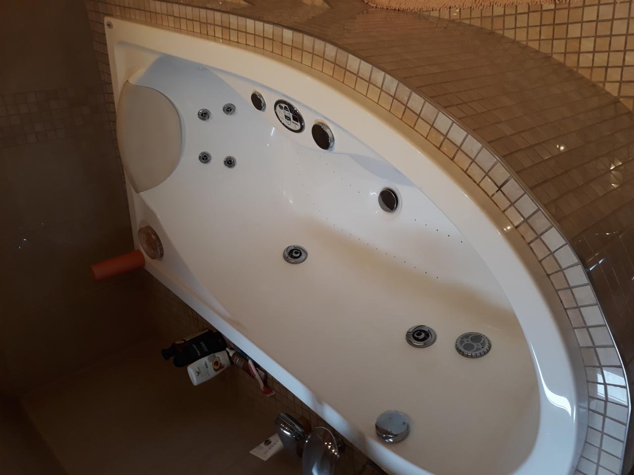 Biała wanna z hydromasażem, obudowana mozaiką w odcieniach brązu, zamontowana w łazience w Rybniku. Widoczne dysze i elementy sterujące.