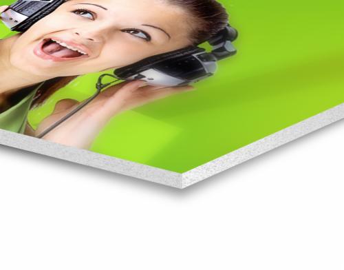 Zdjęcie kobiety z otwartymi ustami, słuchawkami na uszach i telefonem przy głowie, umieszczone na zielonej płycie piankowej.