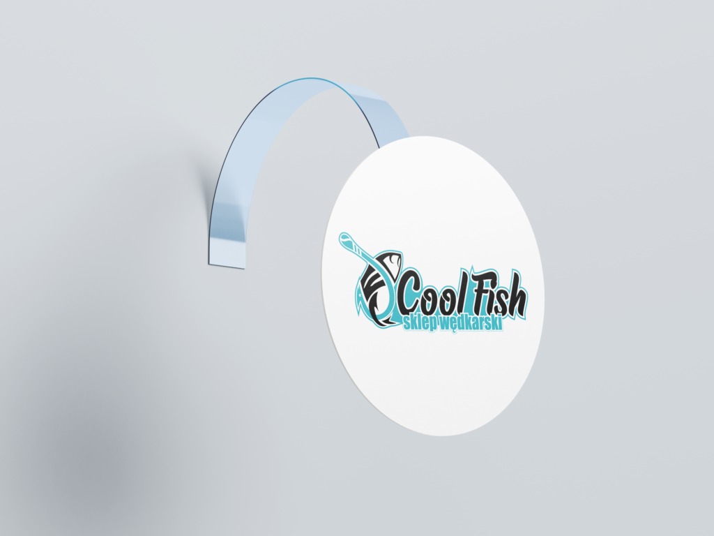 Okrągła naklejka z logo 'Cool Fish sklep wędkarski' przymocowana do ściany za pomocą przezroczystego plastikowego haczyka, w kolorystyce błękitno-czarnej.