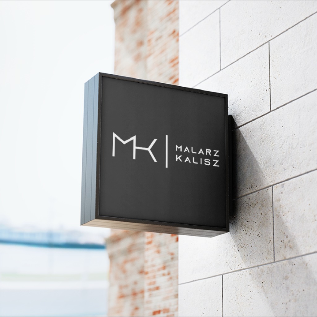 Czarny, kwadratowy szyld z logo 'MK' i napisem 'Malarz Kalisz', zamontowany na jasnej, kamiennej ścianie budynku.