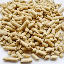 Stos jasnych, cylindrycznych brykietów z biomasy na białym tle, widoczne drobne włókna drzewne w strukturze.