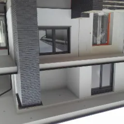 Nowoczesny dom w trakcie budowy, widoczne okna z czarnymi ramami, murowany komin z szarej cegły, fragment rusztowania i okno zabezpieczone folią.