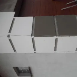 Montaż sufitu z płyt kartonowo-gipsowych z widocznymi łączeniami szpachlowanymi na szaro, fragment okna wentylacyjnego w tle.