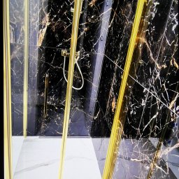 METAMORFOZA WNĘTRZ KRZYSZTOF JAGUCKI - Kabina prysznicowa z czarnymi marmurowymi płytkami i złotymi detalami, widok z góry, biała marmurowa podłoga, nowoczesny design.