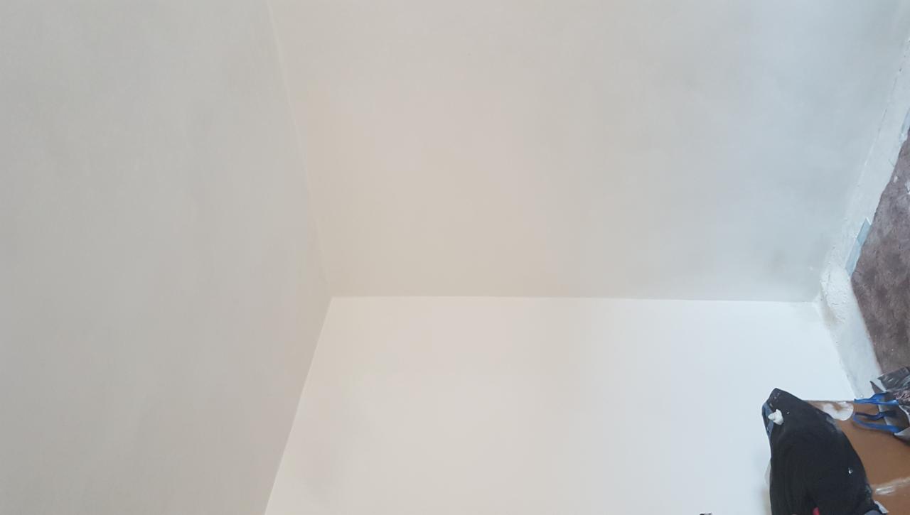 Świeżo wyszpachlowany róg pomieszczenia z widoczną gładką powierzchnią ścian i sufitu, gotową do malowania.