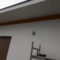 Elewacja budynku z zamontowanymi roletami zewnętrznymi w Gołuchowie, widoczny fragment rusztowania i narzędzia.