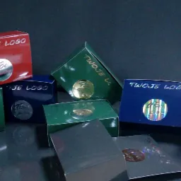 Kolekcja kolorowych pudełek z nadrukowanym logo firmy i błyszczącymi naklejkami, prezentacja różnych wariantów personalizacji opakowań.