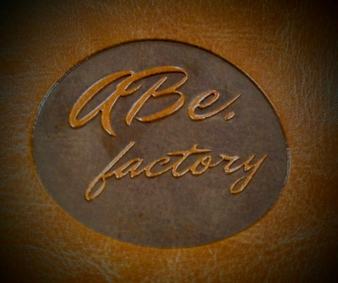 Brązowa skóra z wytłoczonym logo 'ABe. factory' w okręgu.