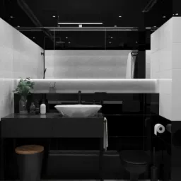 Nowoczesna łazienka z czarno-białymi płytkami o strukturze liści, umywalką w kształcie diamentu i minimalistyczną armaturą, oświetlona listwą LED nad umywalką.