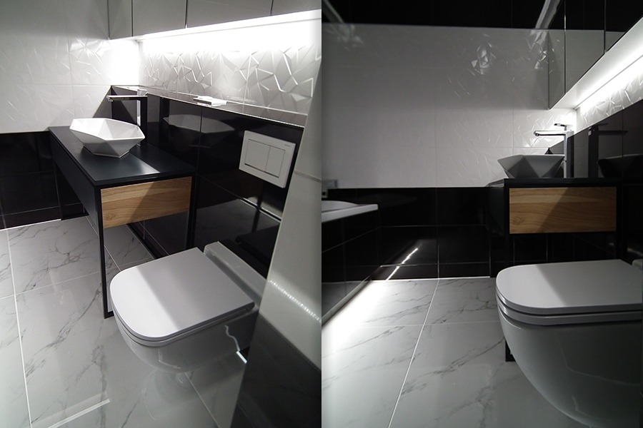 Nowoczesna łazienka z biało-czarnymi płytkami o geometrycznym wzorze, wisząca misa WC, umywalka nablatowa o kształcie diamentu na czarnym blacie z drewnianą szufladą, oświetlenie LED pod szafkami...