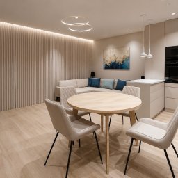Dolecińska Projekt DARIA DOLECIŃSKA - Jasne, nowoczesne wnętrze: salon z aneksem kuchennym. Okrągły stół z krzesłami, sofa z poduszkami, minimalistyczne oświetlenie i drewniana ściana. Spokojna kolorystyka.