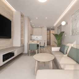 Dolecińska Projekt DARIA DOLECIŃSKA - Nowoczesny salon z aneksem kuchennym, beżowa sofa z zielonymi poduszkami, okrągły drewniany stolik kawowy. Duży telewizor na panelu z jasnego drewna, stół jadalny z zielonymi krzesłami. Oświetlenie...