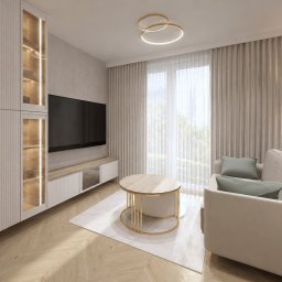 Dolecińska Projekt DARIA DOLECIŃSKA - Beżowa sofa, okrągły stolik kawowy ze złotą, ażurową podstawą. Szafa z ryflowanymi frontami i podświetlanymi witrynami. Drewniana podłoga w jodełkę, złota lampa sufitowa z dwoma okręgami.