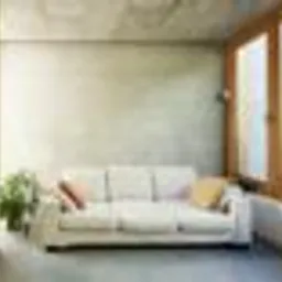 Jasne wnętrze z betonową ścianą, kremową sofą, rośliną doniczkową i dużym oknem z drewnianą ramą. Dwa dekoracyjne poduszki na sofie. Minimalistyczny styl.