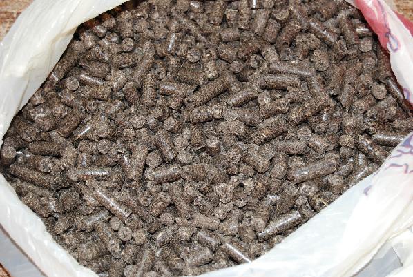 Worek wypełniony ciemnymi granulkami biopaliwa, widoczne drobne nierówności i struktura brykietów.