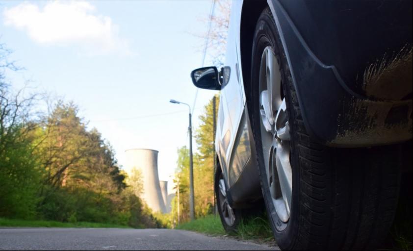 Samochód zaparkowany na poboczu drogi w Brwinowie, w tle widoczne chłodnie kominowe elektrowni.