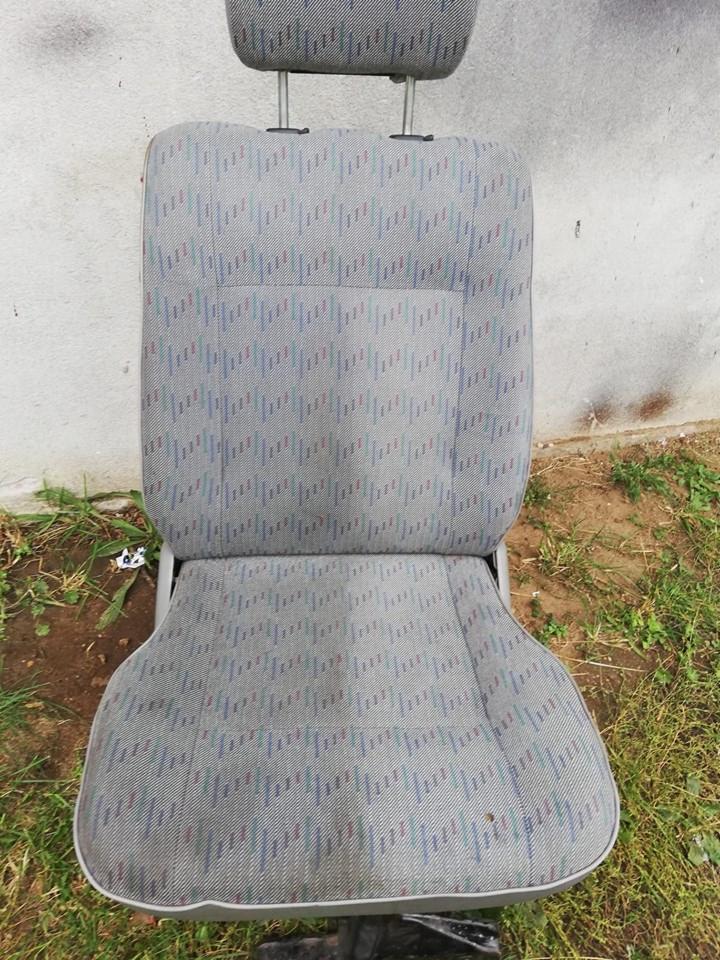 Tapicerowane siedzenie samochodowe z zagłówkiem, wzór w drobne, kolorowe paski, sfotografowane na tle betonowej ściany i trawy.