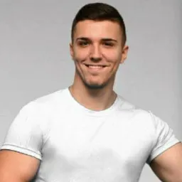 Uśmiechnięty mężczyzna w białym t-shircie na jasnoszarym tle, prezentujący sylwetkę.