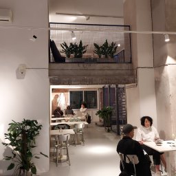 BB Fabrik - Metalowa konstrukcja antresoli z roślinami w kawiarni w Wieliczce. Ażurowa balustrada w kolorze granatowym, nowoczesny design, oświetlenie punktowe.