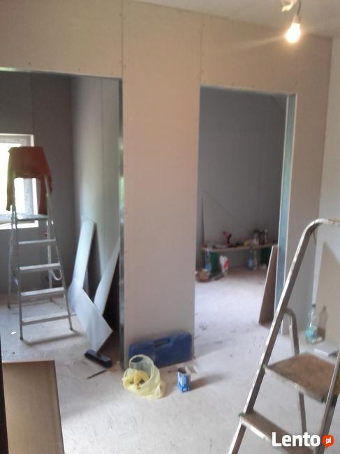 Montaż ścian działowych z płyt kartonowo-gipsowych, widoczne profile, płyty, drabiny, narzędzia i akcesoria budowlane, surowy stan przed wykończeniem.