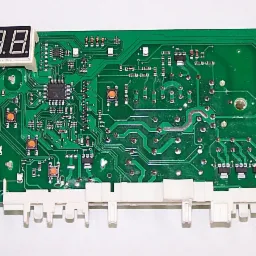 Zdjęcie przedstawia zieloną płytę główną programatora pralki Amica z widocznymi elementami elektronicznymi, przyciskami i białym wyświetlaczem LED z cyframi 88:88, leżącą na białym tle.