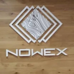 Logo firmy NOWEX na tle drewnianej podłogi, składające się z trzech białych kwadratów ułożonych jeden w drugim oraz panelu z wzorem słojów drewna wewnątrz, całość umieszczona nad napisem 'NOWEX'.