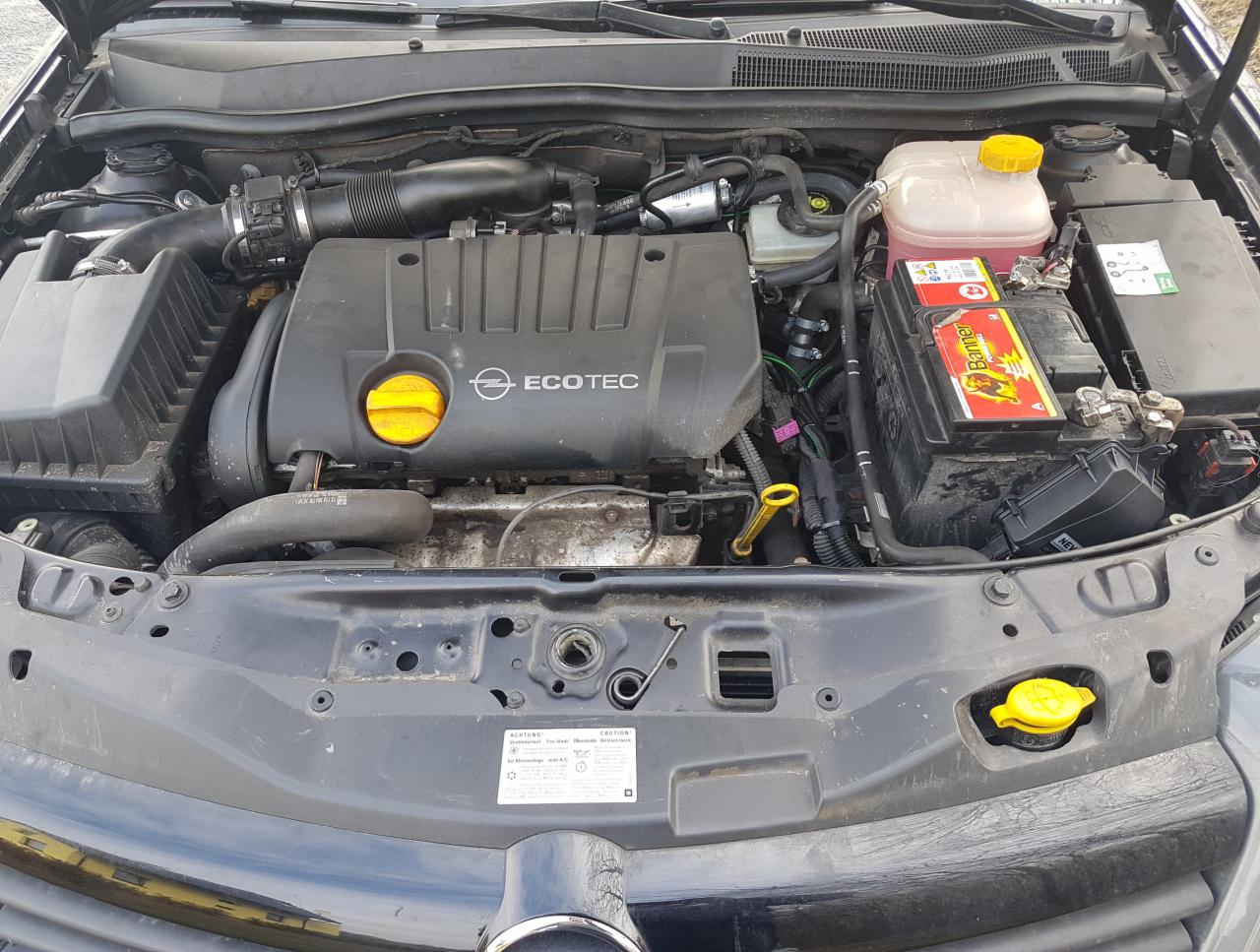 Otwarta maska samochodu z widocznym silnikiem Ecotec, akumulatorem marki Banner i żółtym wskaźnikiem poziomu oleju.