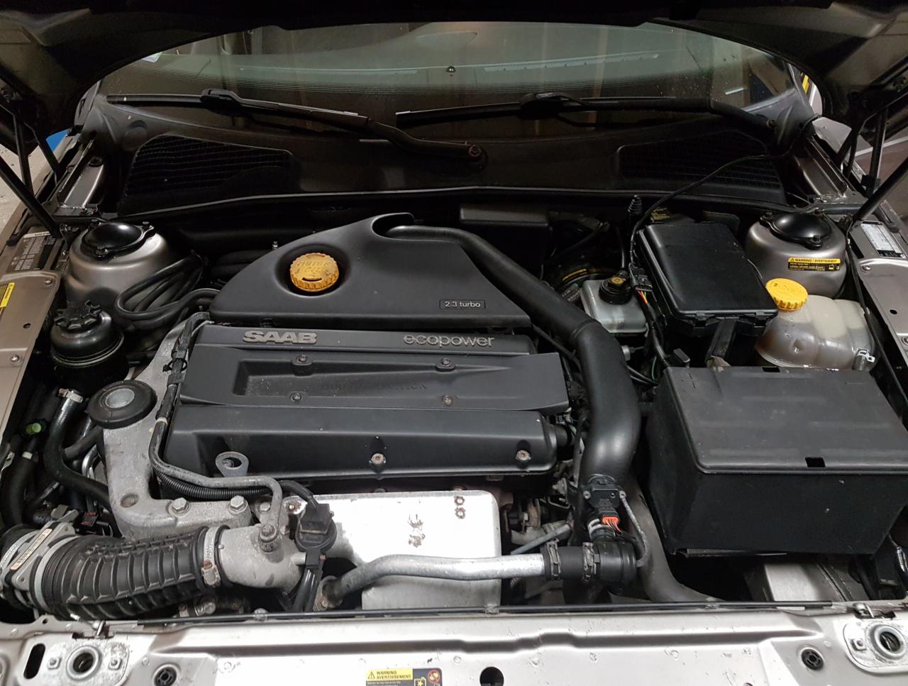 Silnik 2.3 Turbo EcoPower samochodu Saab z otwartą maską, widoczne elementy układu paliwowego i elektrycznego, zbliżenie na blok silnika i osprzęt.