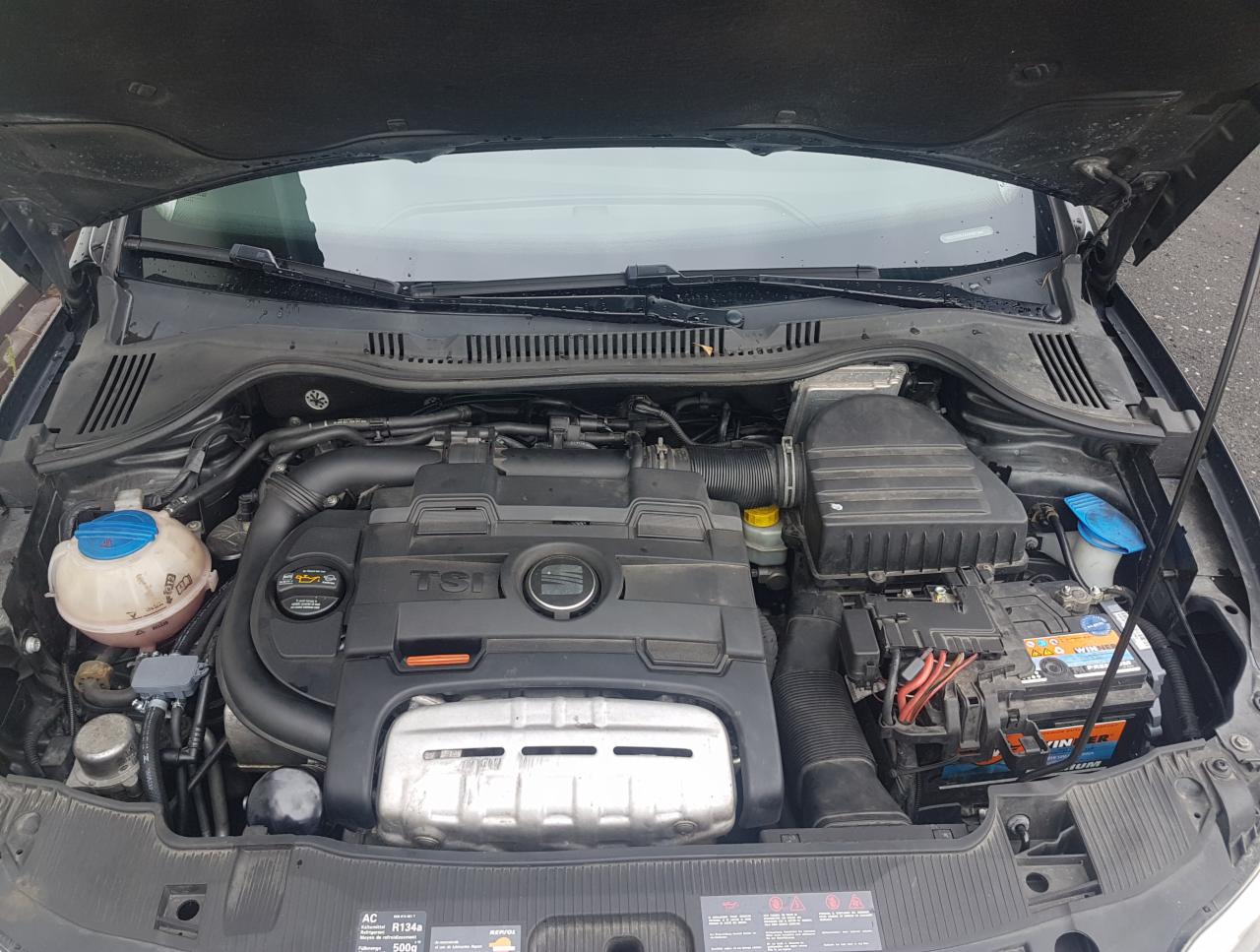 Otwarta maska samochodu z widocznym silnikiem TSI, akumulatorem Winner i zbiornikiem płynu chłodniczego z niebieską nakrętką.