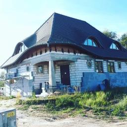 Usługi Ogólnobudowlane Dawid Plesner - Dom w trakcie budowy: murowane ściany z białej cegły silikatowej, nietypowy dach z lukarnami, widoczne bloczki betonowe i rusztowanie.