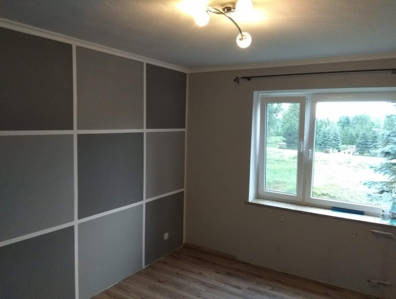 Pokój po malowaniu ścian w geometryczne wzory szarości, z widocznym oknem i drewnianą podłogą.