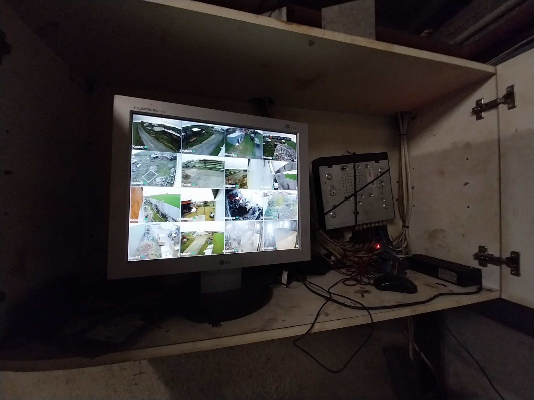 Monitor z widokiem z kamer przemysłowych, rejestrator DVR z przewodami w szafce.