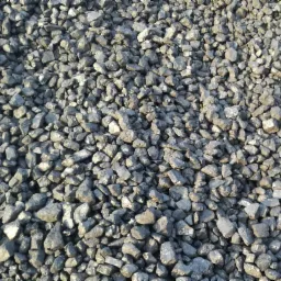 Kupa antracytu w nierównym oświetleniu, widoczne pojedyncze bryłki o nieregularnych kształtach i błyszczącej powierzchni.