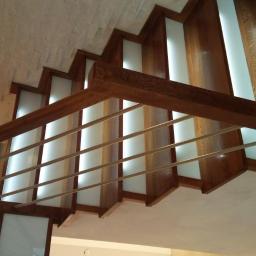 HAŁYS-Meble - Nowoczesne schody drewniane z podświetlanymi stopniami i metalową balustradą, widok od dołu.