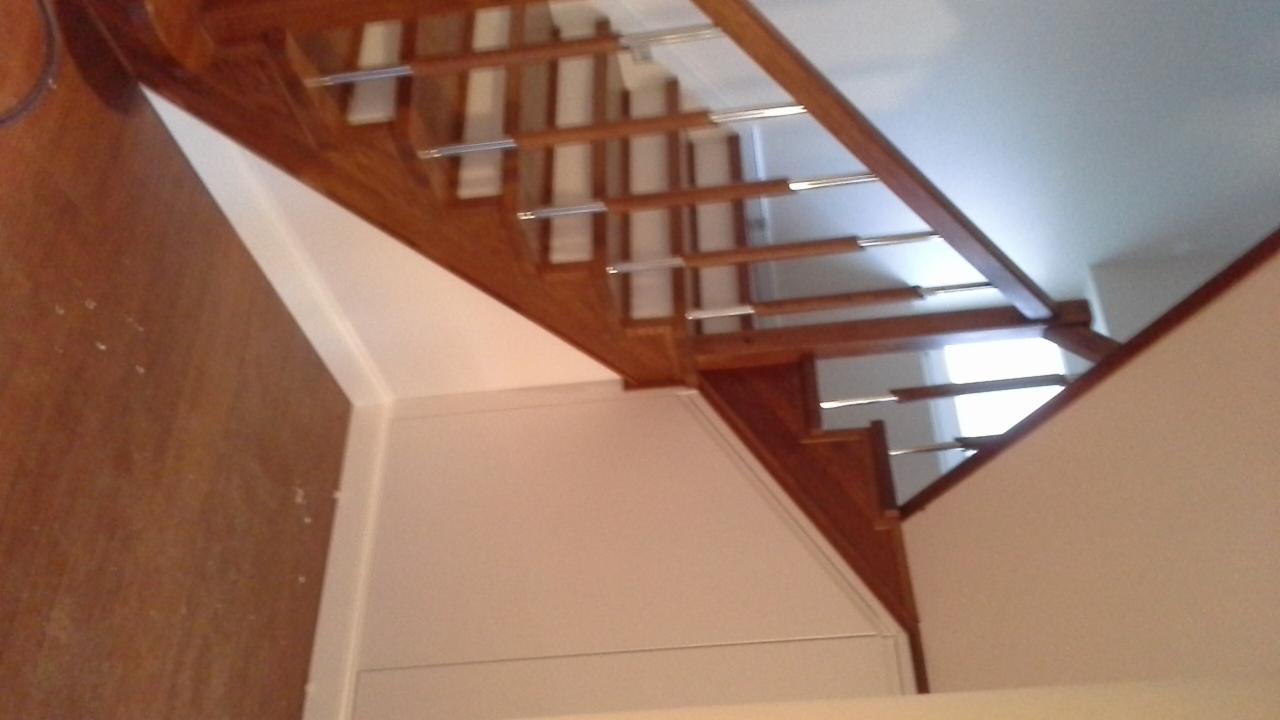 Wnętrze z drewnianymi schodami z metalowymi wspornikami, widok z dołu, ukazujący konstrukcję i wykończenie.