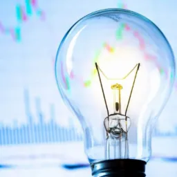 Żarówka na tle wykresu giełdowego, symbolizująca oszczędność energii i inwestycje.