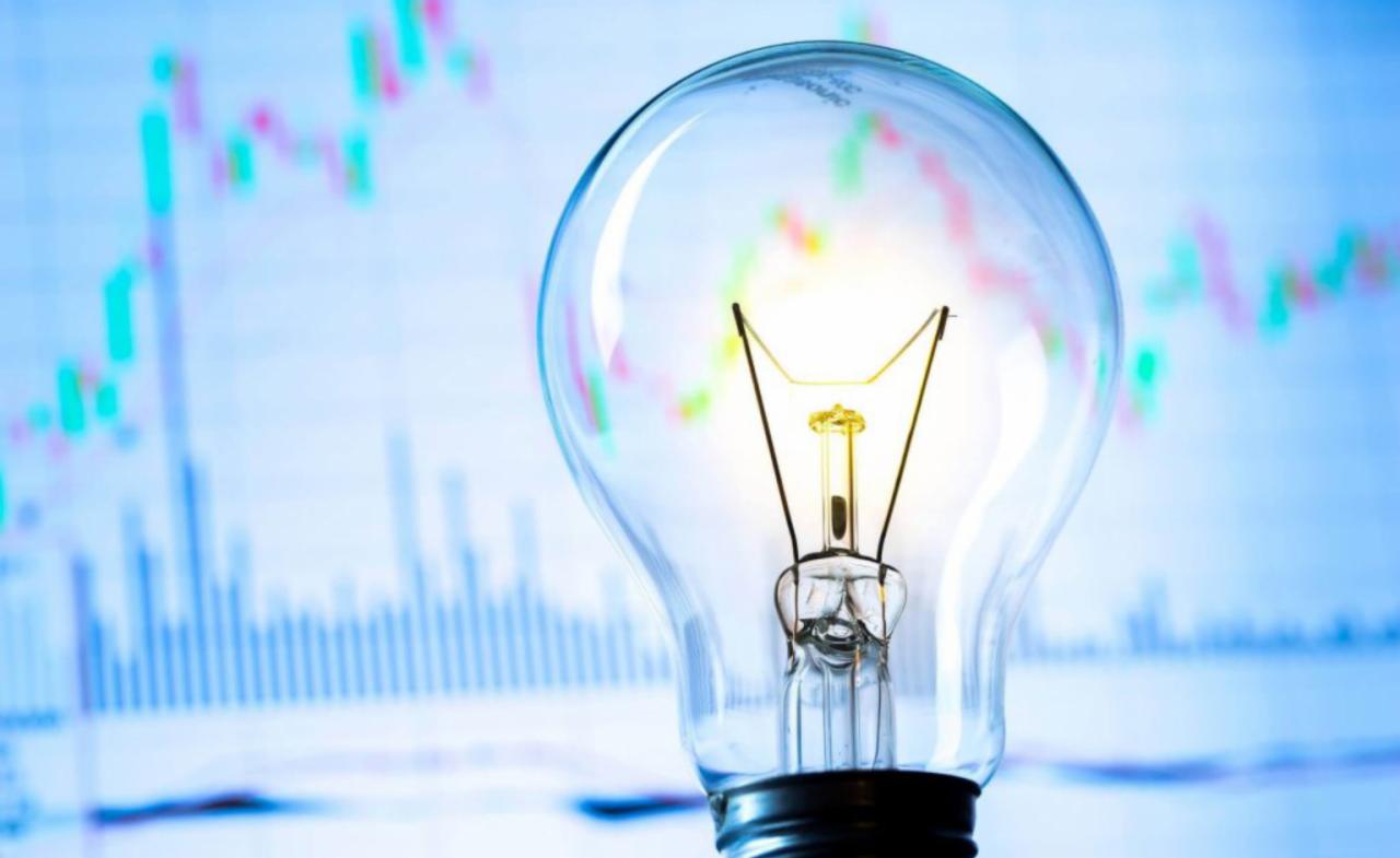 Żarówka na tle wykresu giełdowego, symbolizująca oszczędność energii i inwestycje.