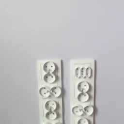 Białe, podwójne gniazdka elektryczne natynkowe różnego typu zamontowane na ścianie, widok z bliska, gniazdka posiadają bolce uziemiające.