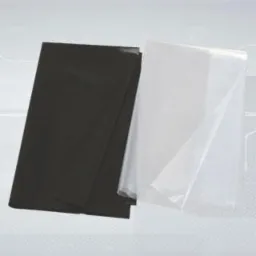 Dwa arkusze folii: czarny i przezroczysty, ułożone warstwami na jasnoszarym tle z delikatnym gradientem.