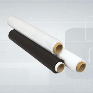 Dwa wałki folii stretch, jeden biały, drugi czarny, oparte o siebie na tle z delikatnym wzorem kropek.