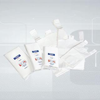 Zestaw białych, foliowych toreb z nadrukowanym logo i grafiką, ułożonych na jasnym, rozmytym tle. Widoczne różne rozmiary i rodzaje toreb, zarówno płaskie, jak i z uchwytami.