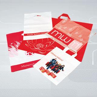Zestaw różnorodnych toreb reklamowych z nadrukami w odcieniach czerwieni i bieli, ułożonych na jasnym tle. Widoczne motywy kwiatowe, logo firmy 'mw' oraz grafika rodzinna na jednej z toreb.