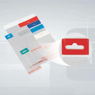 Przezroczyste woreczki foliowe z kolorowymi zawieszkami (czerwone, niebieskie, zielone), prezentowane na szarym tle z delikatnym wzorem.