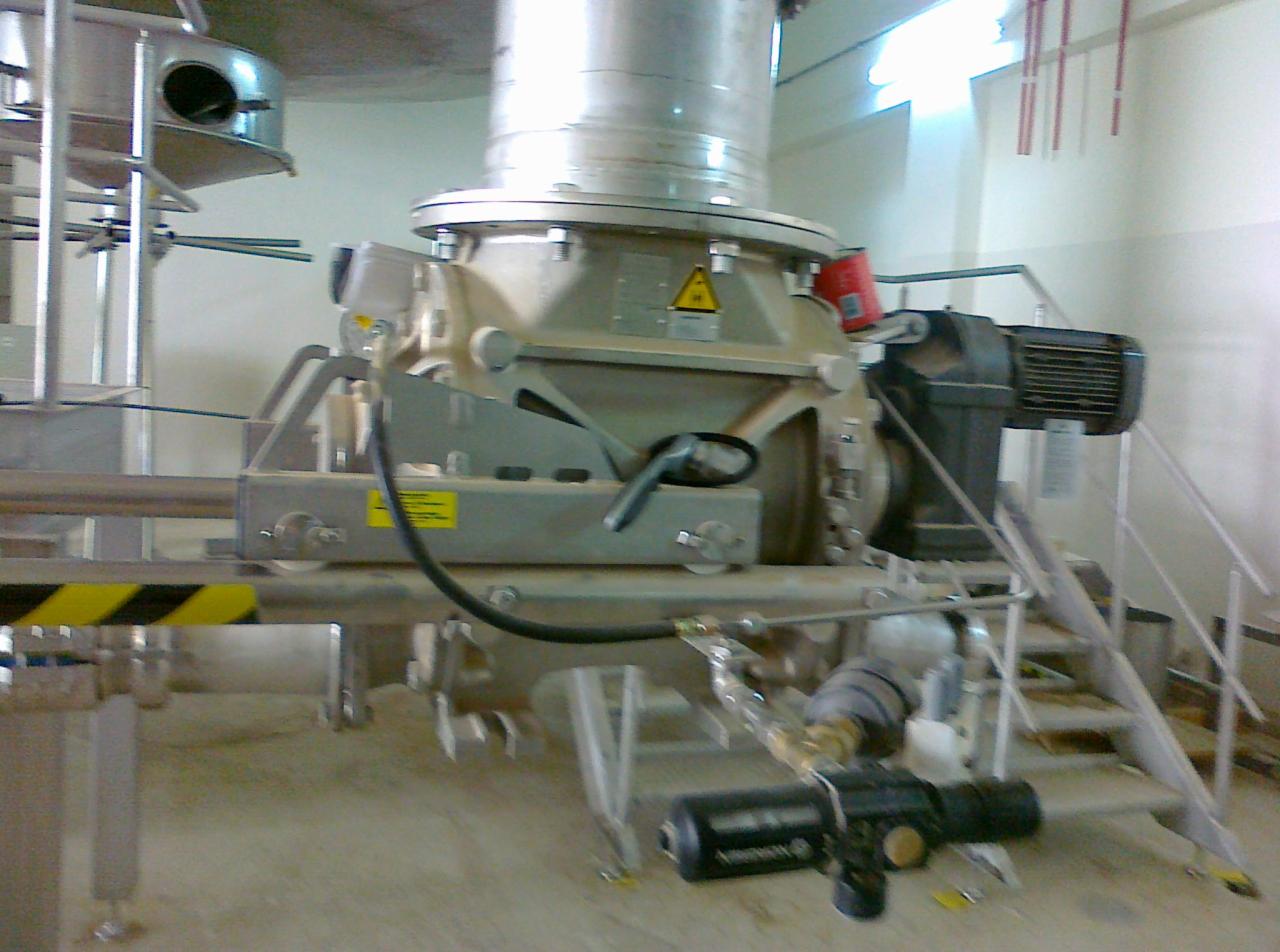 Złożona przemysłowa konstrukcja stalowa z silnikiem elektrycznym, rurami i elementami mocującymi w hali produkcyjnej, z widocznymi schodami dostępowymi.