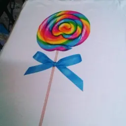 Biała koszulka z nadrukiem lizaka w tęczowych kolorach, ozdobionego niebieską kokardką.