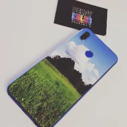 Etui na telefon z nadrukowanym krajobrazem łąki i nieba, obok wizytówka drukarni 'Pełny Kolor'.