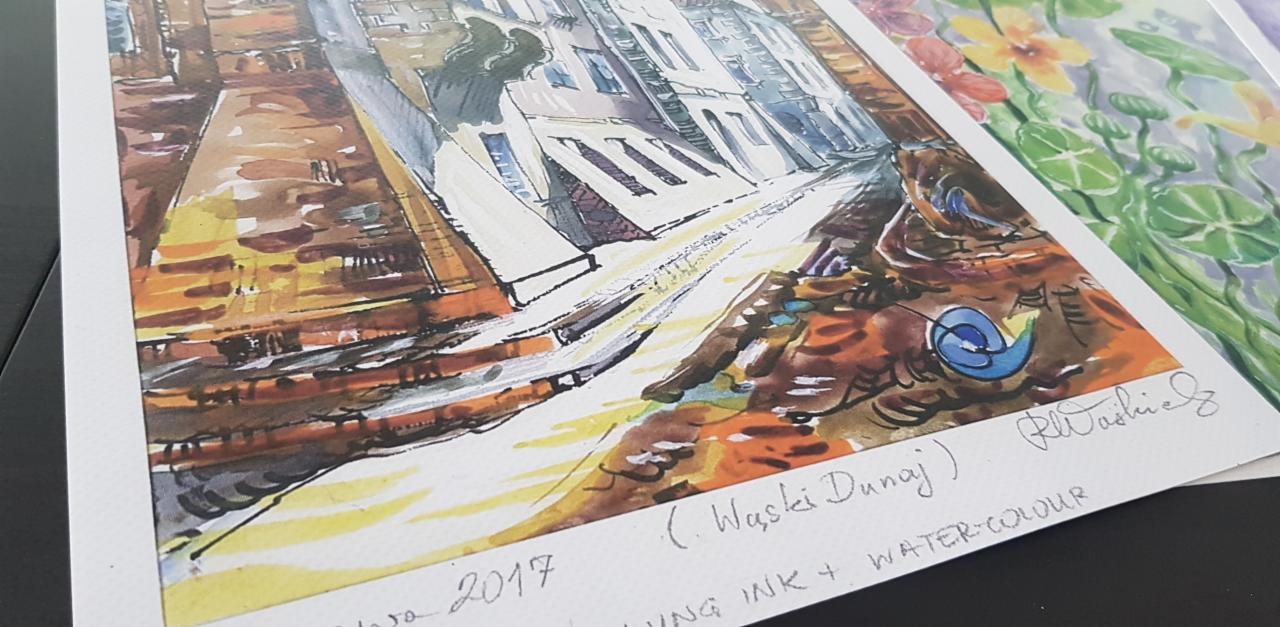 Akwarela przedstawiająca uliczkę miejską z budynkami w perspektywie, obok widoczne fragmenty innych akwareli z motywami kwiatowymi.