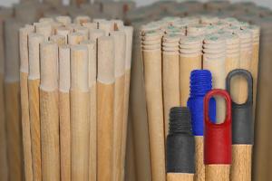 Zestaw drewnianych trzonków do narzędzi ogrodniczych z plastikowymi uchwytami w kolorach: niebieskim, czerwonym i czarnym, ułożonych w pęczki.
